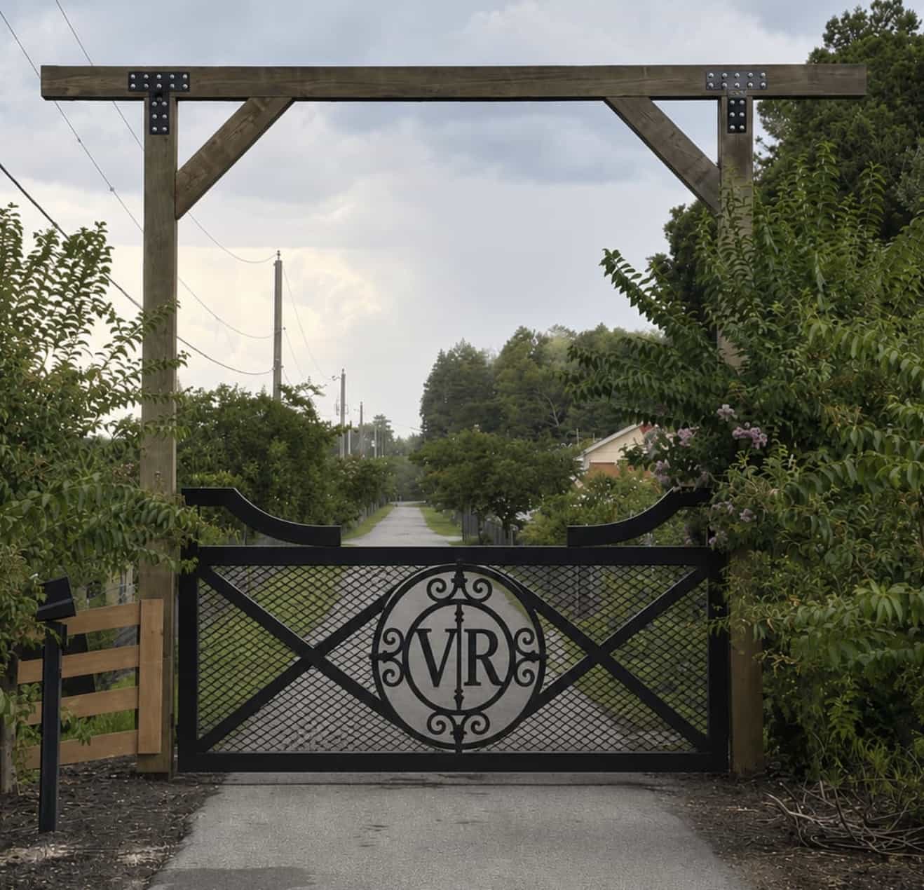 Custom steel driveway gate with a hand-built monogram centerpiece and mesh infill. — Tampa Bay, FL